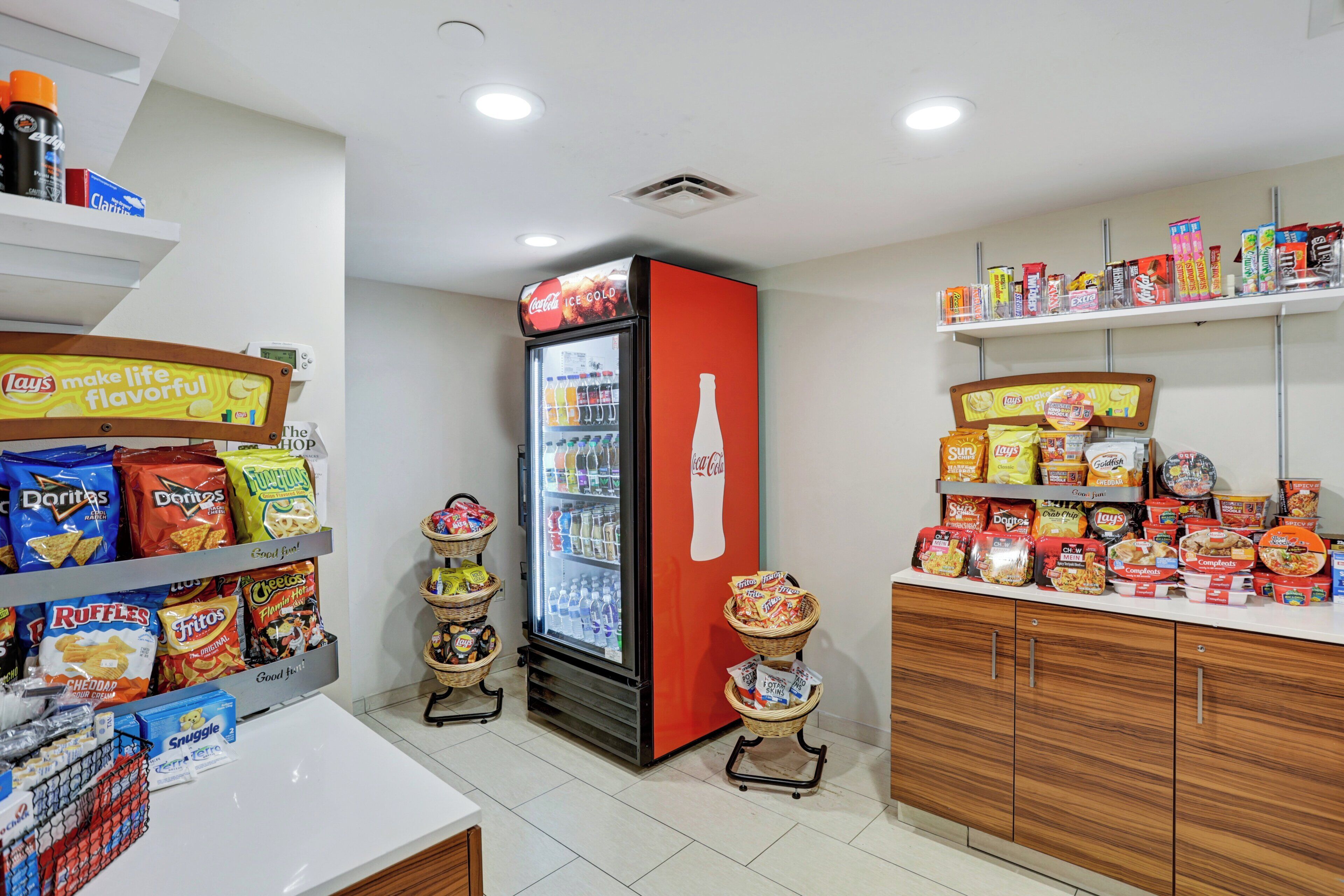 A snack and beverage section with a Coca-Cola refrigerator, snack bins, and shelves stocked with various snacks.