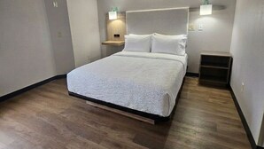 Un dormitorio con cama, mesitas de noche e iluminación en la pared.