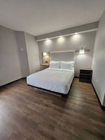 Un dormitorio con cama, mesitas de noche e iluminación en la pared.