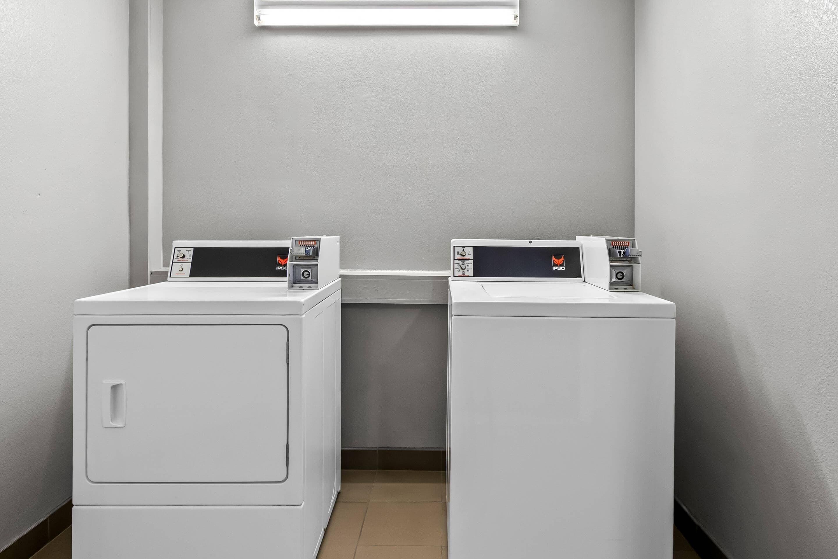 Two white front-loading washing machines in a laundry room with a light fixture above.