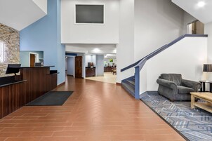 Un moderno vestíbulo de hotel con una recepción, una escalera y una zona de estar.