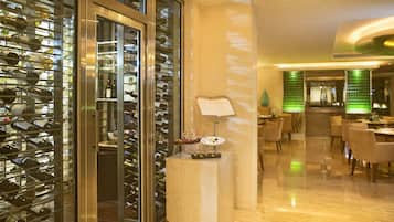 Un vestíbulo de hotel con una bodega de vinos, un mostrador de recepción y un comedor.