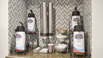 A coffee station with multiple dispensers and a coffee machine, set against a tiled backsplash.