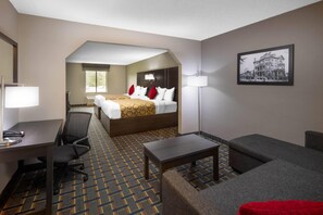 A hotel room with a bed, desk, chair, and a small table. - Baymont by Wyndham Pooler/Savannah (Pooler)