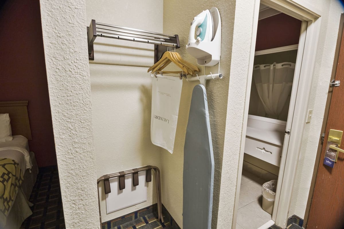 Une salle de bain équipée d’un porte-serviettes, d’une serviette suspendue, d’un rideau de douche, de toilettes et d’une petite fenêtre.