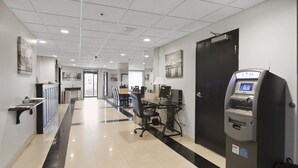 A hotel lobby with a reception desk, a computer station, an ATM, and a door.