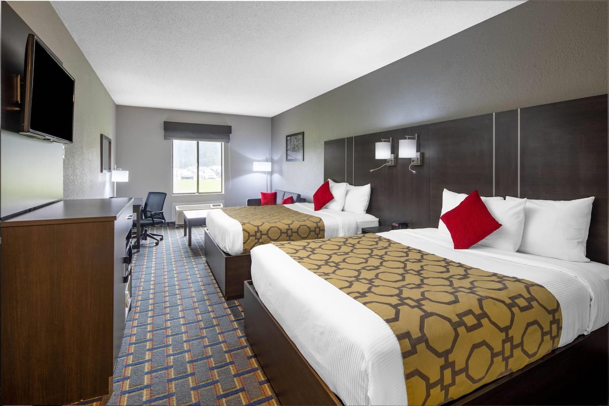 Une chambre d’hôtel avec deux lits, un bureau, une chaise, une télévision et une fenêtre.