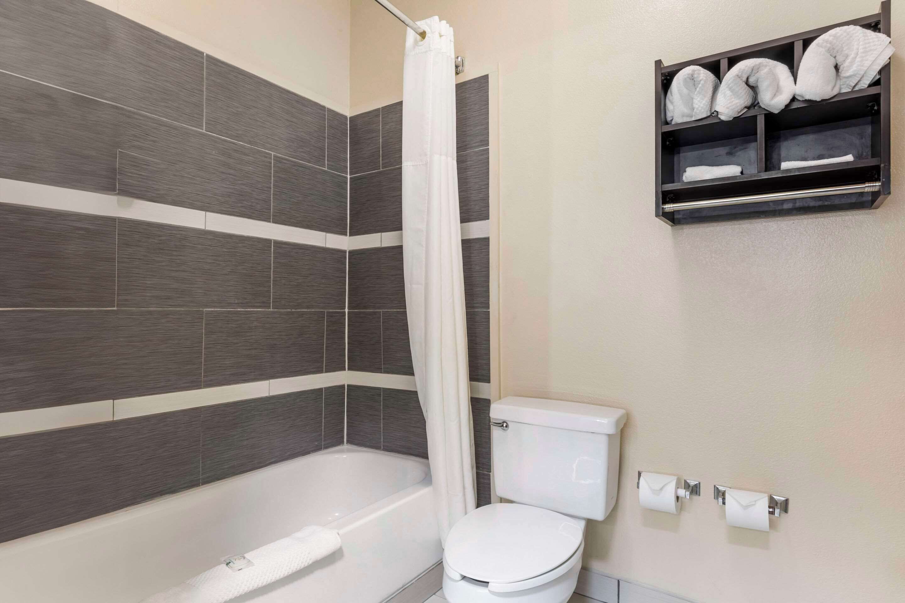 Une salle de bain avec une baignoire, des toilettes et une étagère avec des serviettes.