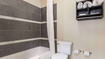 Une salle de bain avec une baignoire, des toilettes et une étagère avec des serviettes.