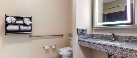 Une salle de bain équipée de toilettes, d’un lavabo, d’un miroir et d’un porte-serviettes avec des serviettes pliées.