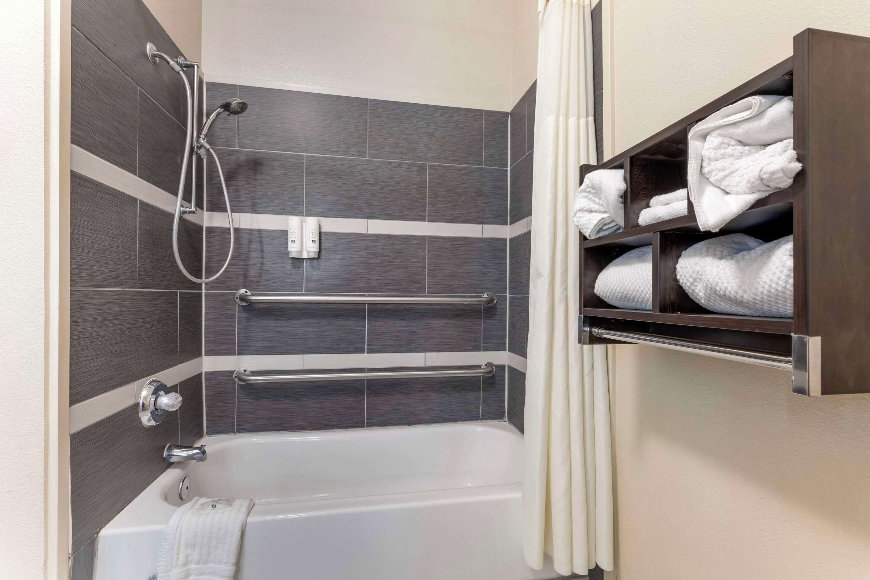 A modern bathroom with a bathtub, shower, and towel rack.