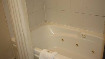 Una bañera blanca con una toalla colgada al lado, cortina de ducha y paredes de azulejos.