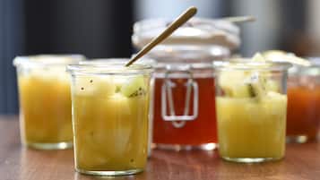 Three glass jars with a spoon, one jar with a lid, and a blurred background.