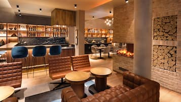 A modern lounge area with leather sofas, round tables, and a fireplace.