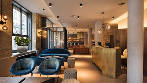 Un interior modern amb una taquilla d'hoste, cadires blaves i una zona de bar.