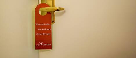 A hotel door with a golden handle and a red sign with multilingual instructions.
