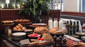 A buffet with various breads, pastries, and cheeses. - Alexandra Barcelona Hotel, Curio Collection by Hilton (Barcelona)