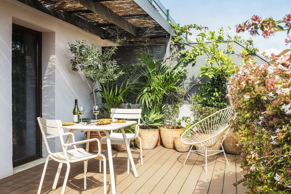 An outdoor patio with a table, chairs, and potted plants.