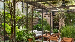 An outdoor patio with a wooden table and chairs, surrounded by lush greenery and a brick wall. - Alexandra Barcelona Hotel, Curio Collection by Hilton (Barcelona)