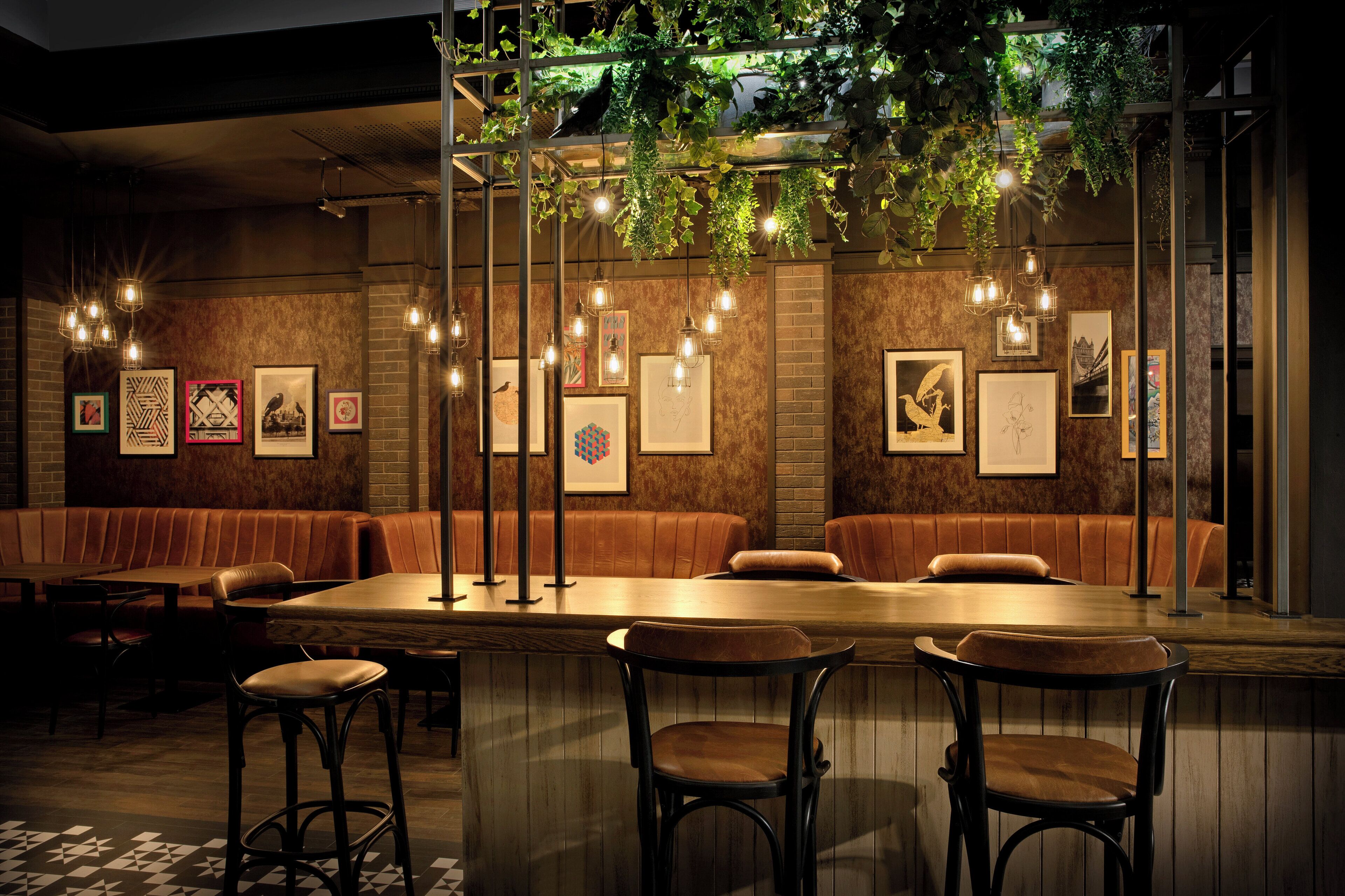 Un restaurante con barra, cabinas y plantas colgantes.