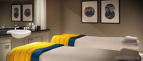A hotel room with two beds, a large mirror, and framed artwork on the wall.