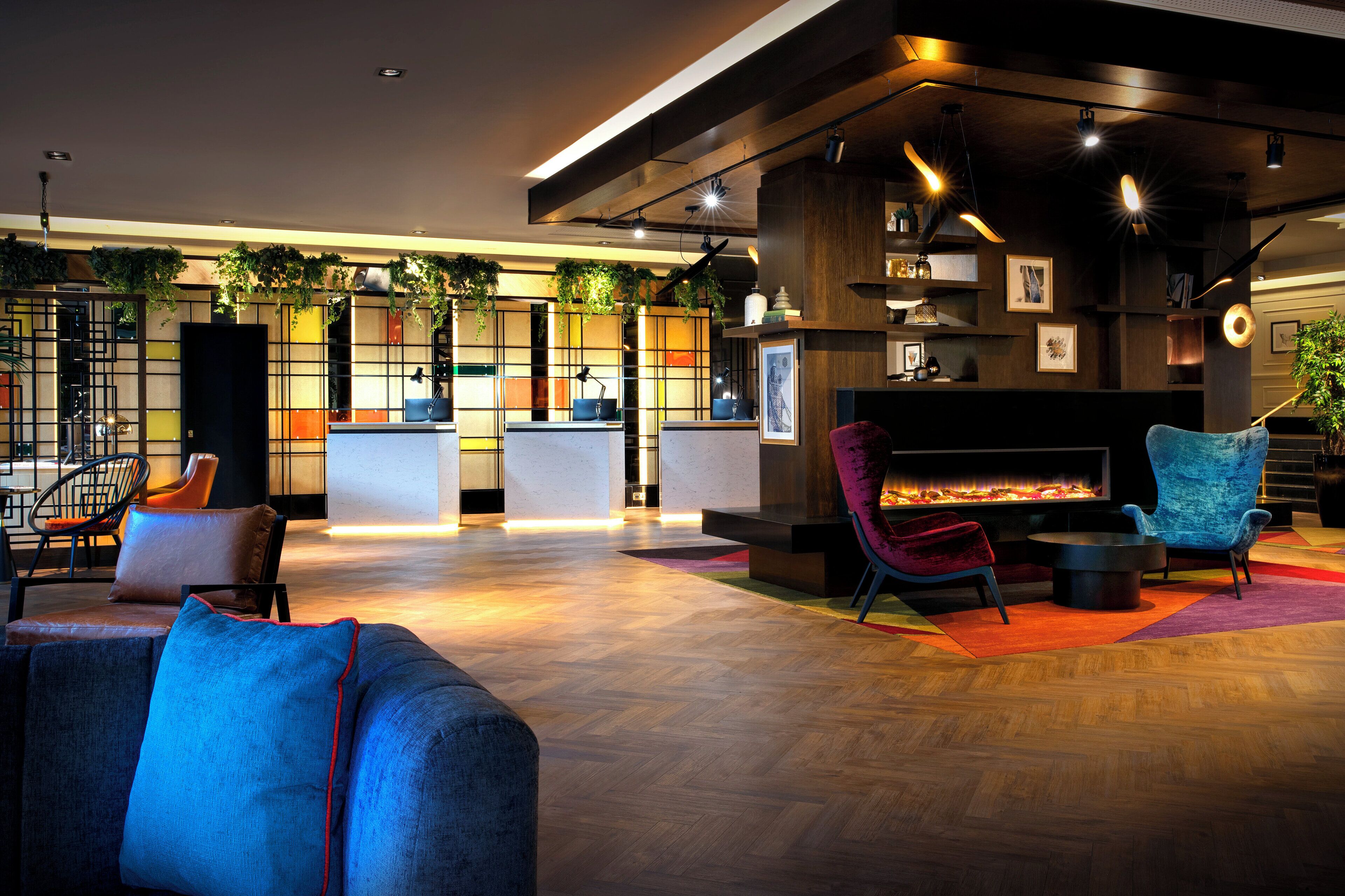 A modern lobby with a reception desk, seating area, and a fireplace.