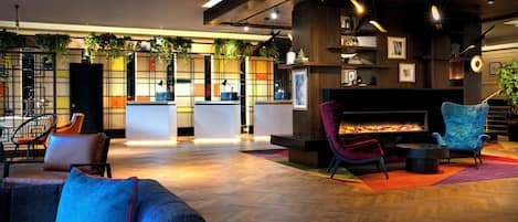 A modern lobby with a reception desk, seating area, and a fireplace.