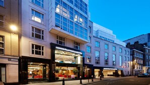 A hotel with a modern facade, large windows, and a well-lit entrance. - Leonardo Royal Hotel London City - Tower of London (London)