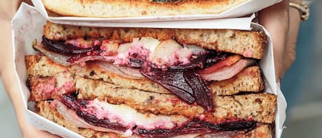 A person holding two sandwiches with visible fillings.