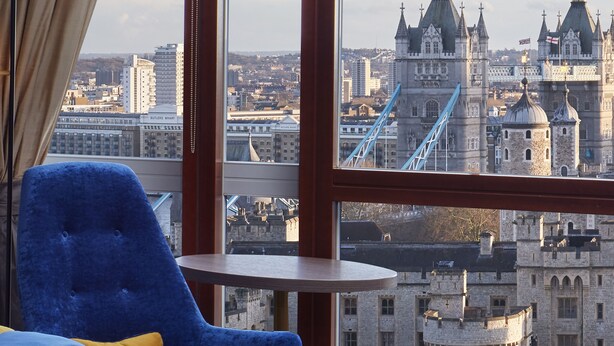 A room with a large window offering a view of historic architecture and a bridge. - Leonardo Royal Hotel London City - Tower of London (London)