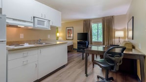 A compact kitchen with a microwave, sink, and a dining area with a table and chairs.