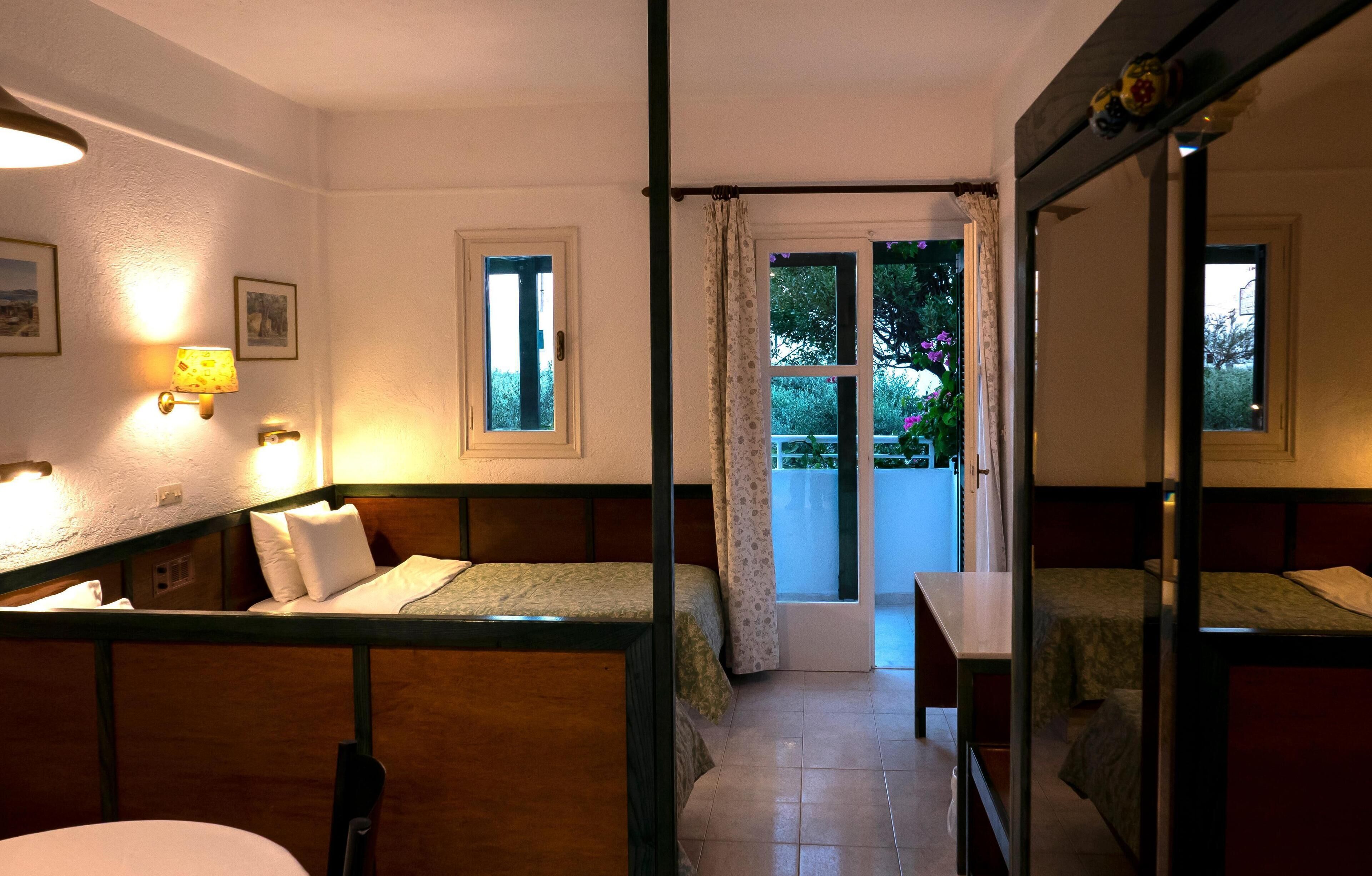 A room with two beds, a table, and a window with curtains.