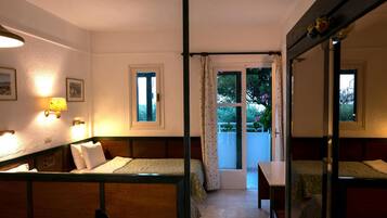 A room with two beds, a table, and a window with curtains.