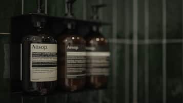 A shelf with three bottles of Aesop Geranium Leaf Body Cleanser.