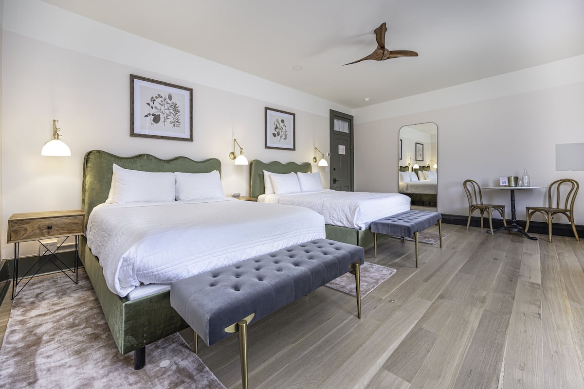 Une chambre d’hôtel avec deux lits, un banc, un bureau et une chaise.