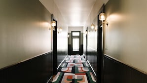 Un couloir avec un tapis à motifs, des appliques murales et une porte au fond.