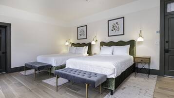 A double bed with a green headboard, two bedside tables with lamps, a bench, and a ceiling fan.