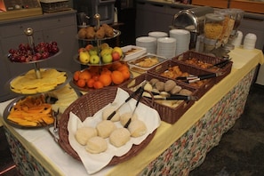 Un bufé con diversas opciones de comida, incluyendo frutas, verduras y panes.