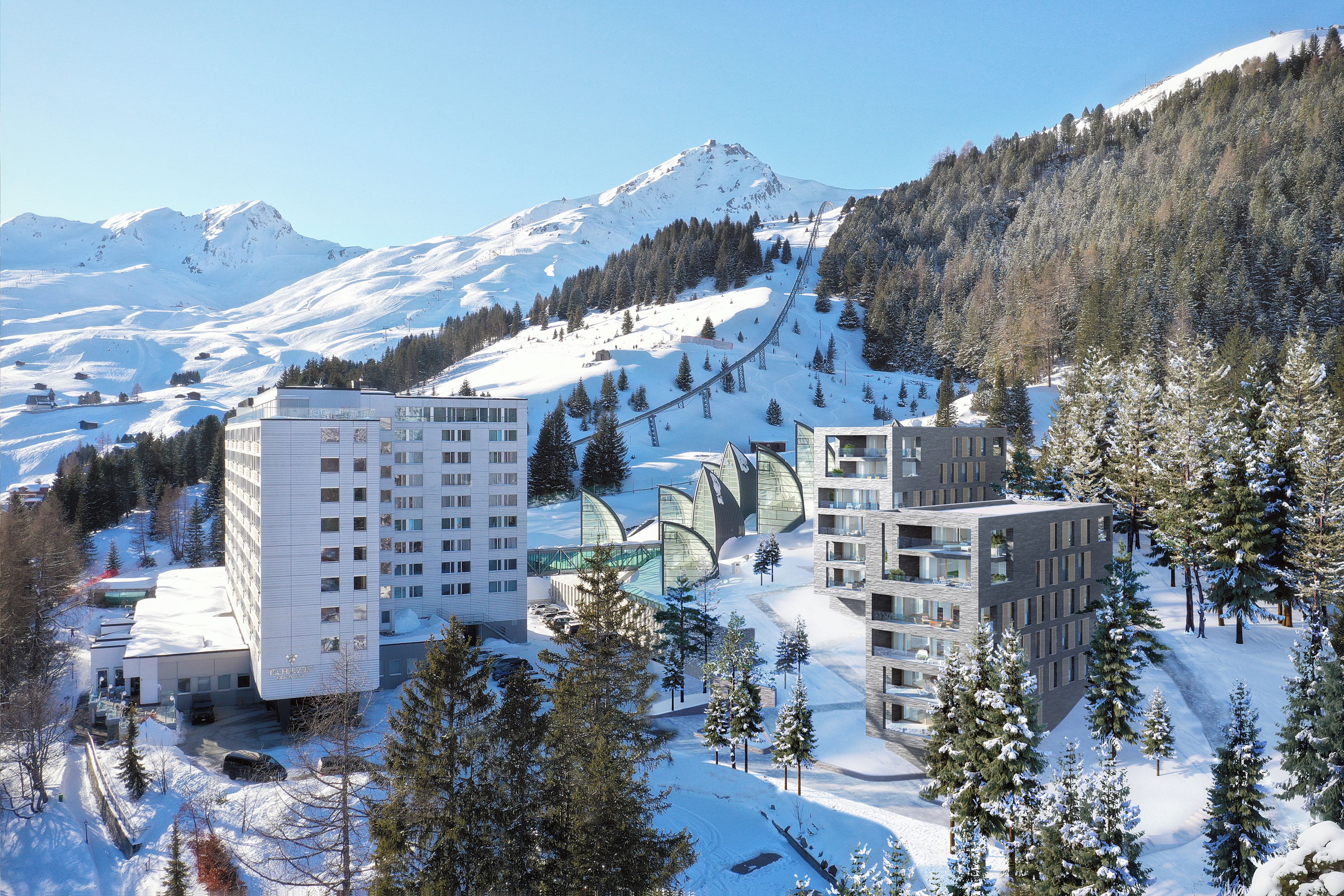 Ein moderner Hotelkomplex mit mehreren Gebäuden, umgeben von schneebedeckten Bergen und Bäumen.