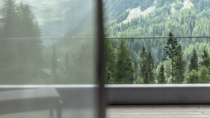 Una habitación con un ventanal que da a un paisaje montañoso boscoso.