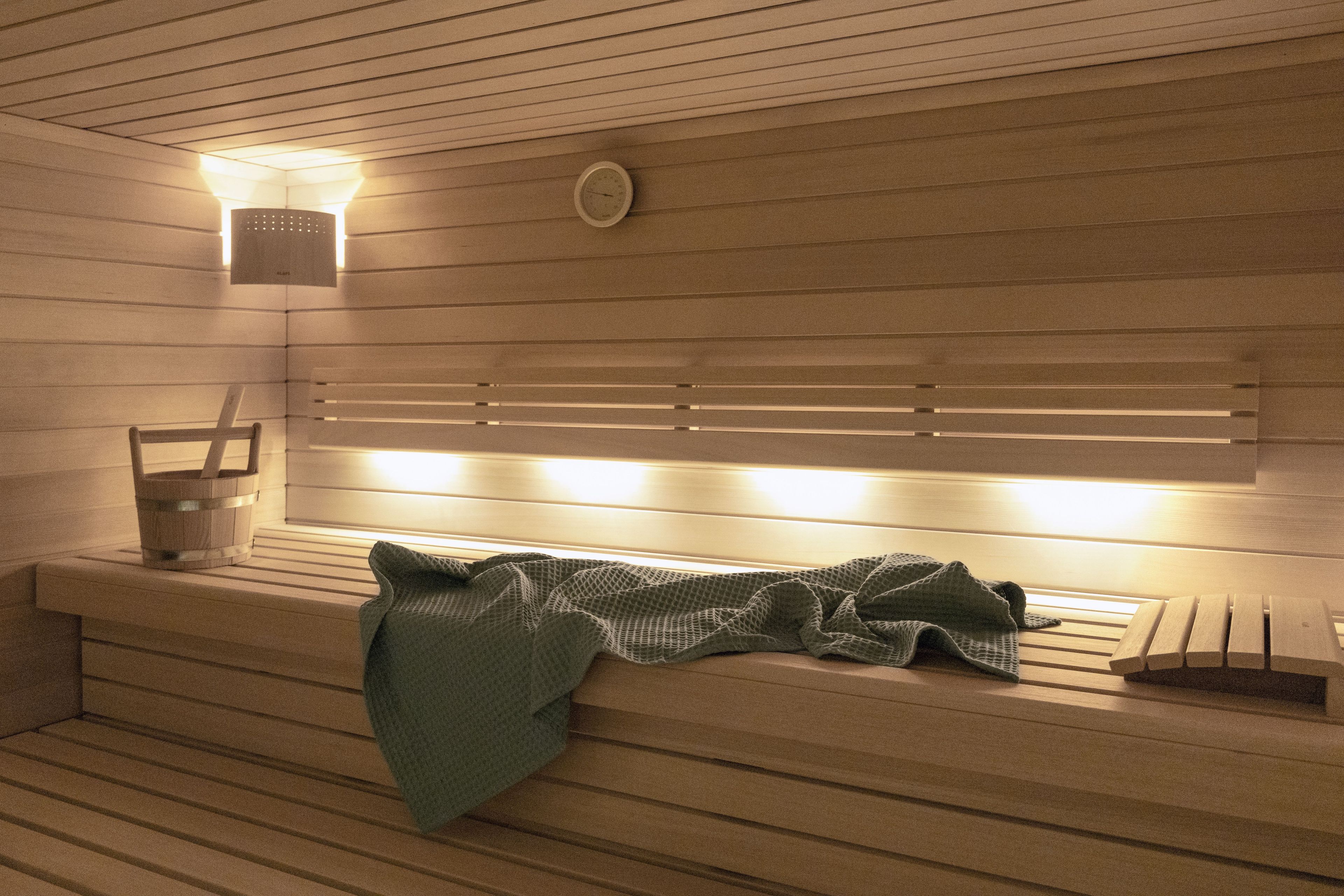 Un sauna avec des bancs en bois, un chauffage intégré aux bancs et une horloge fixée au mur.