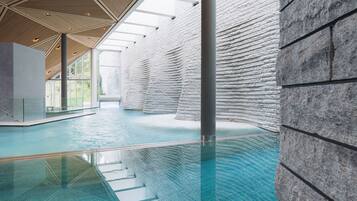 Ein modern gestalteter Innenpool mit großzügigem Raum, hoher Decke und einer Reihe von Steinwänden.