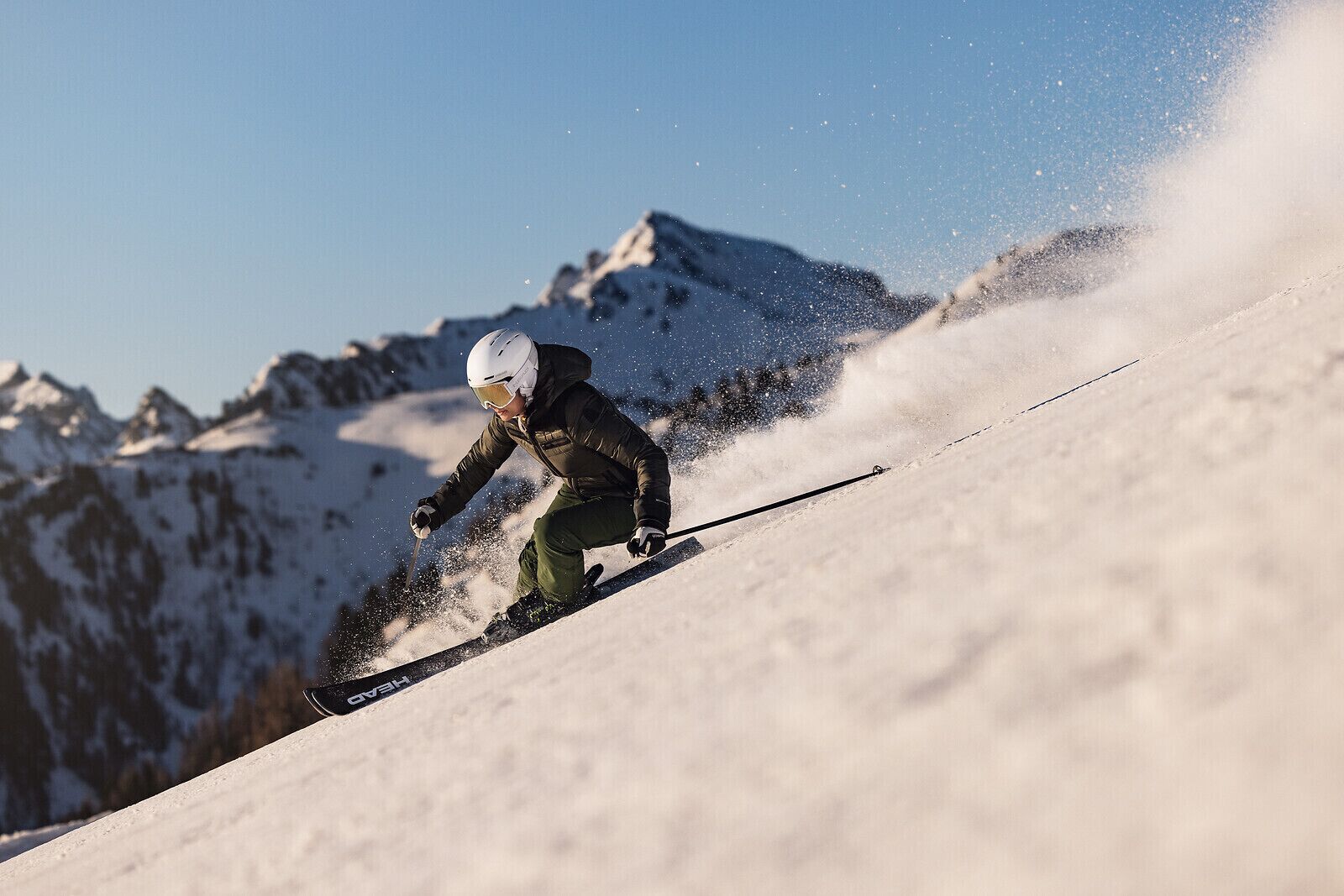 A person skiing down a snowy slope with a mountain in the background.