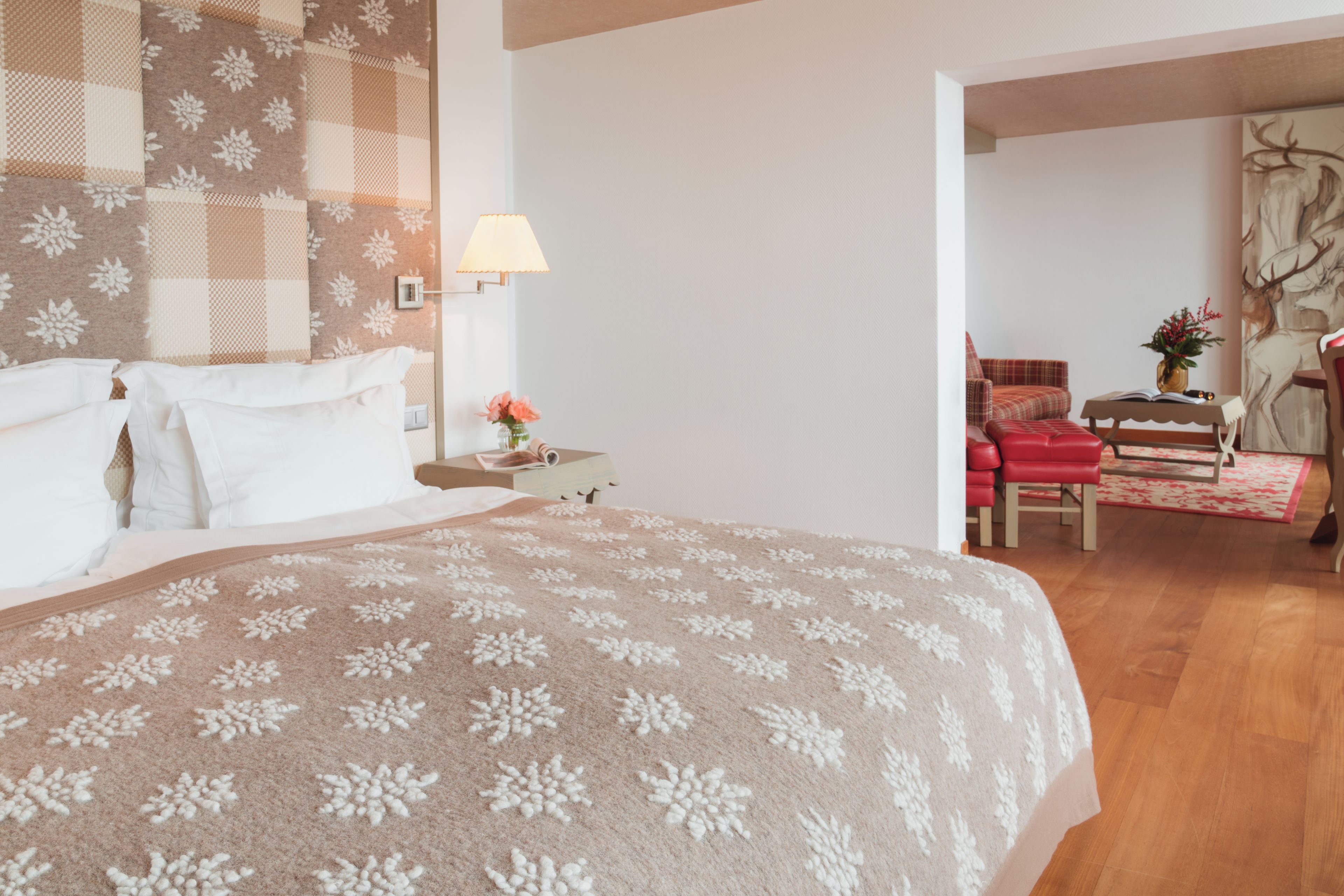A hotel room with a large bed, a desk, a chair, and a painting on the wall.