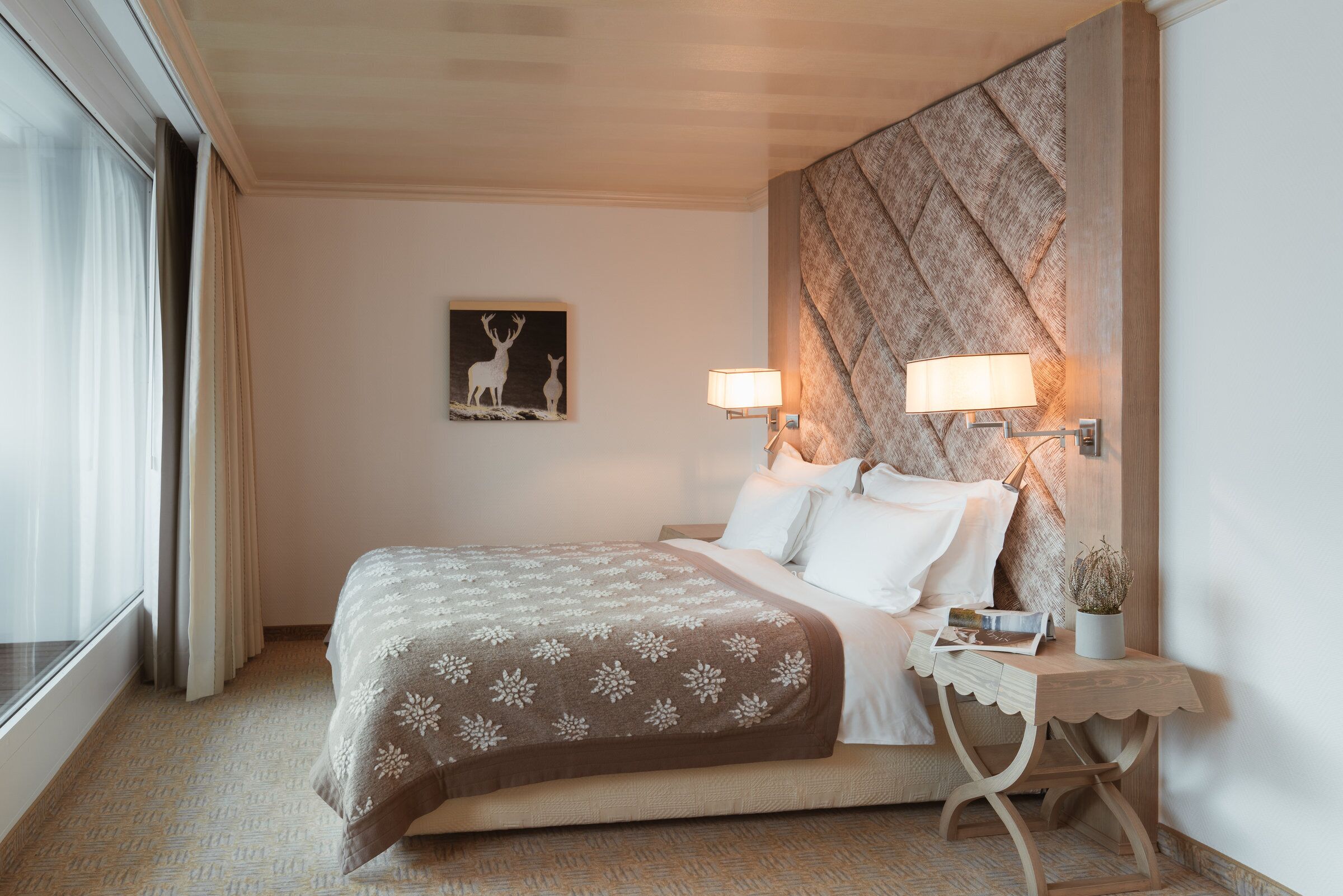 Une chambre d’hôtel avec un lit, des lampes de chevet, une table de chevet, un tableau encadré au mur et une fenêtre avec des rideaux.