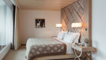 Une chambre d’hôtel avec un lit, des lampes de chevet, une table de chevet, un tableau encadré au mur et une fenêtre avec des rideaux.