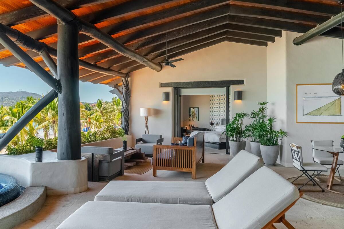 A modern outdoor lounge area with lounge chairs, a sofa, and a dining table.