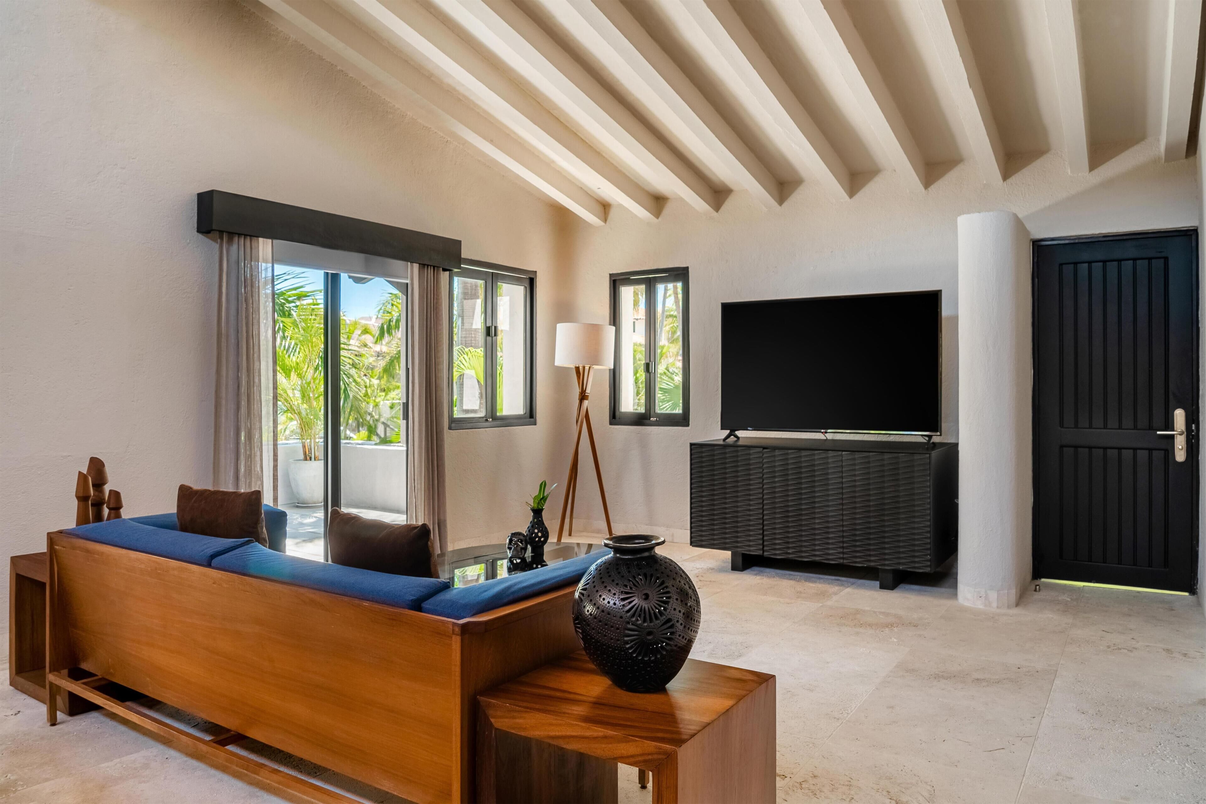 A modern living room with a sofa, a large flat-screen TV, and a decorative vase.