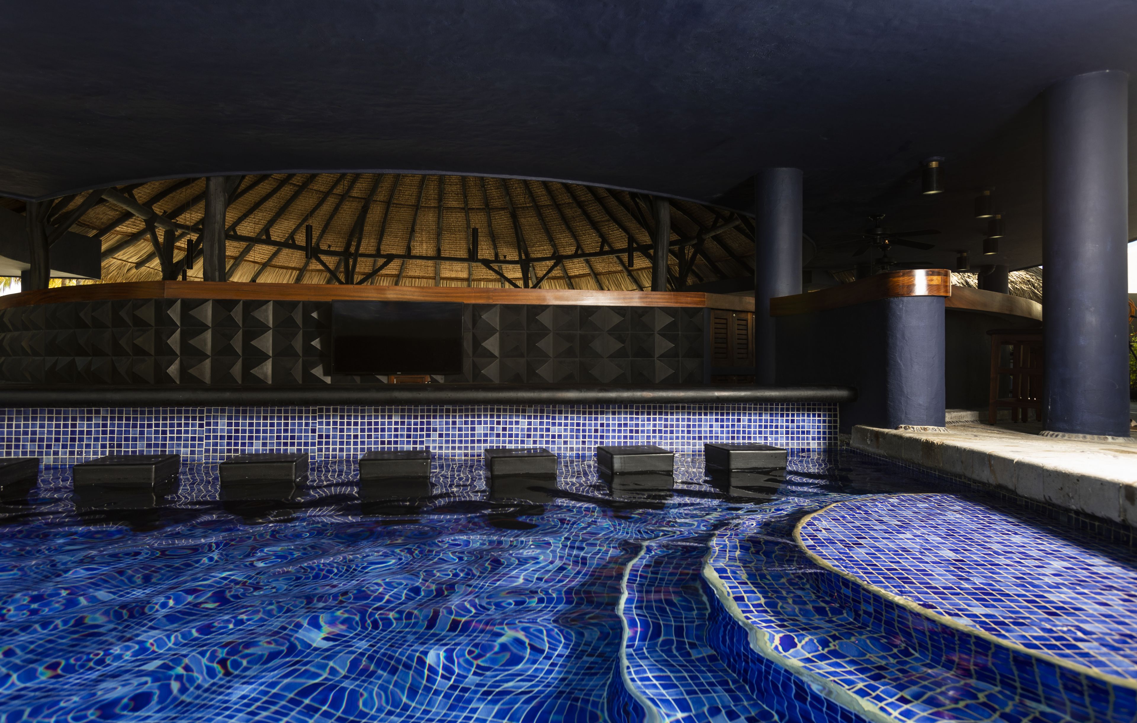 A swimming pool with blue mosaic tiles and a wooden deck area.