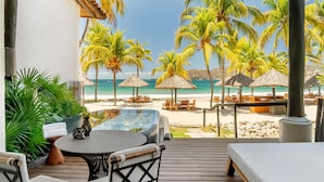 Un espacio de descanso techado al aire libre con vistas a la playa y palmeras.
